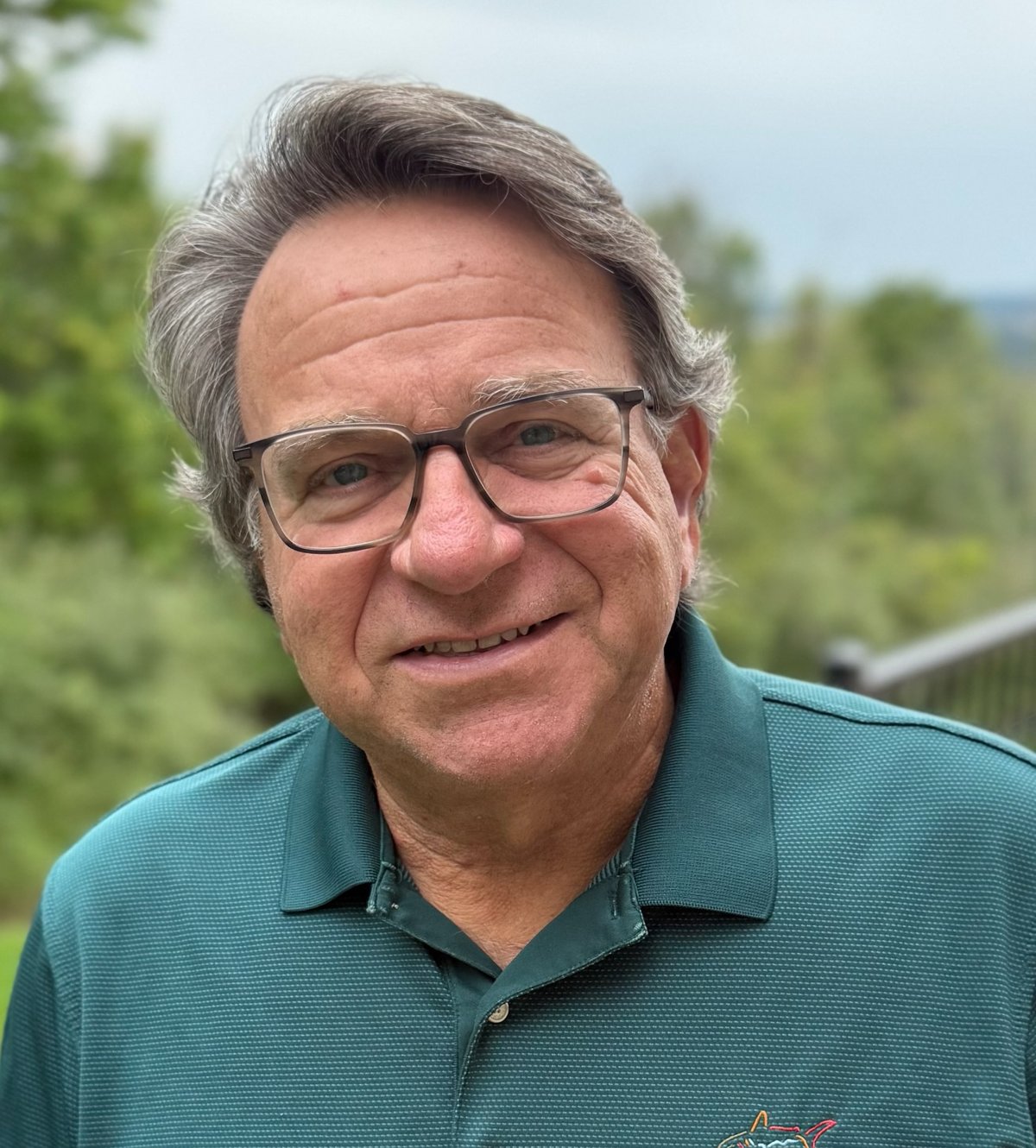 Executive coach John R. Rodgers, smiling outdoors in a green polo